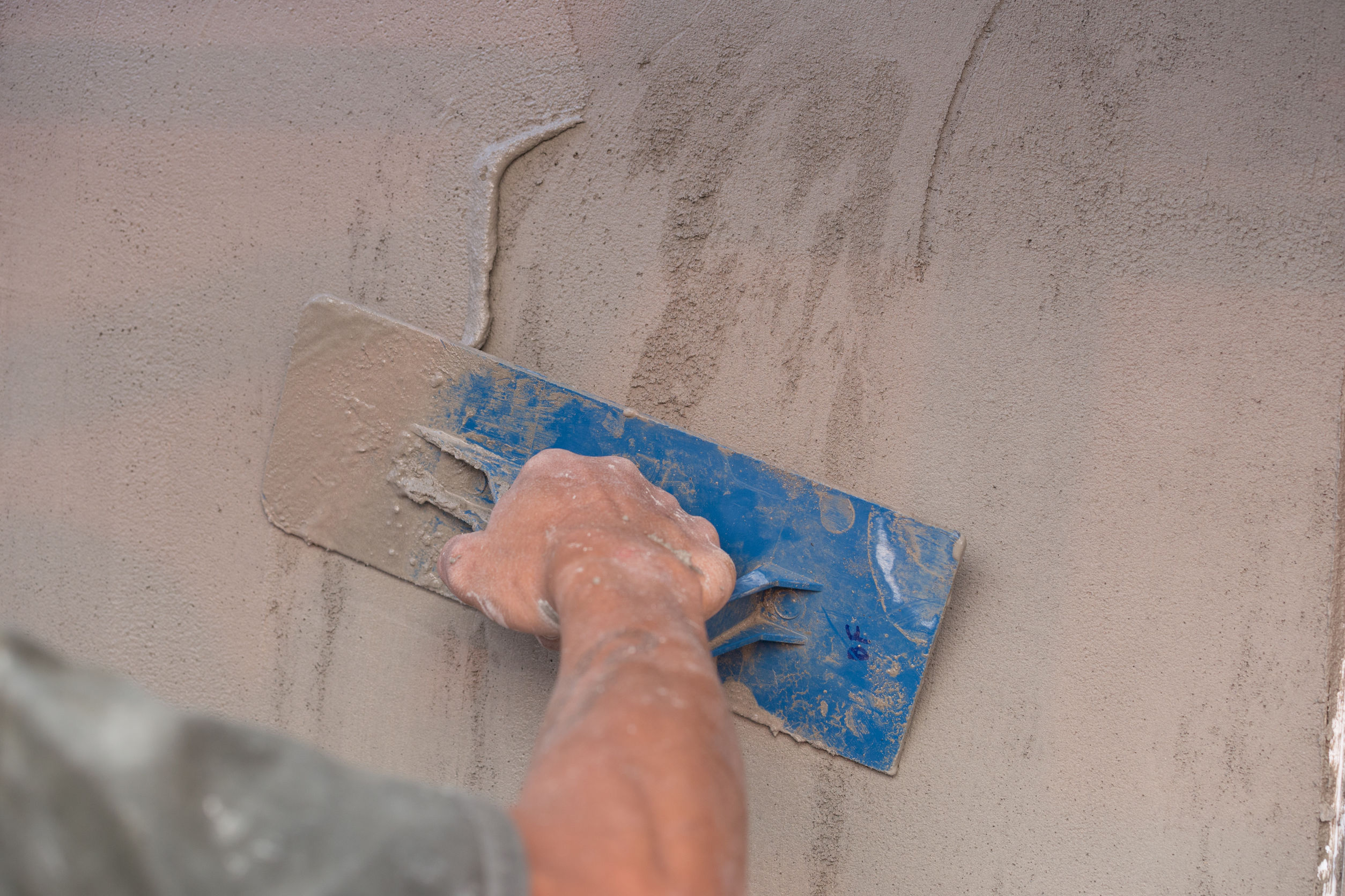 Arbeiter zieht mit Spachtel Verputz an der Wand glatt